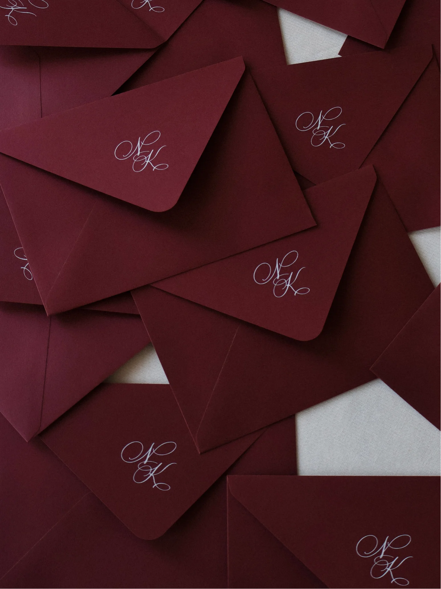 Czerwone kartki papeterii ślubnej z dekoracyjną czcionką w białym kolorze.