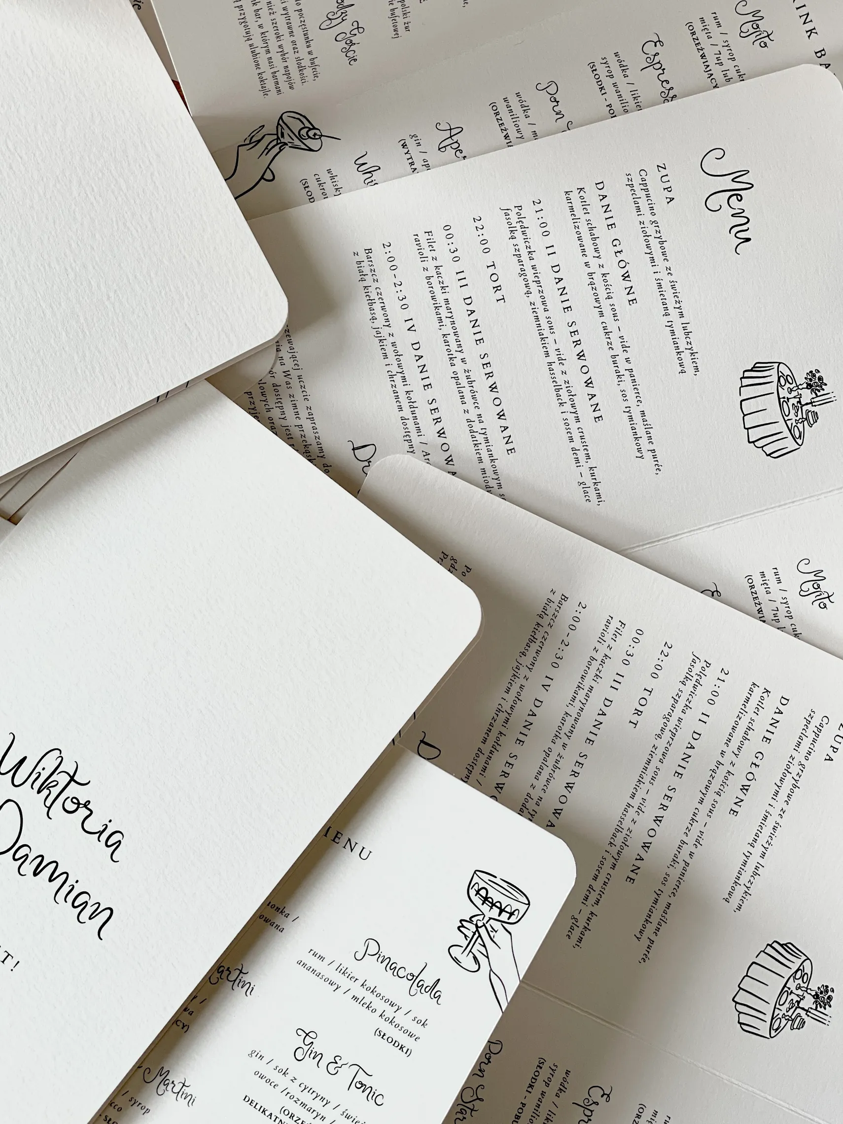 Białe kartki papeterii ślubnej z dekoracyjną czcionką w czarnym kolorze.