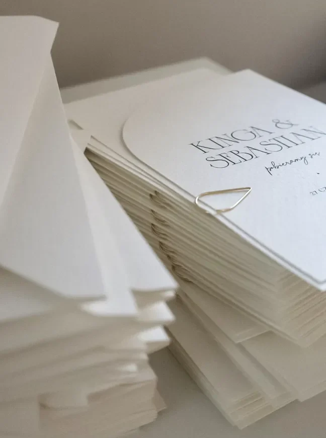 Białe kartki papeterii ślubnej z dekoracyjną czcionką w czarnym kolorze.