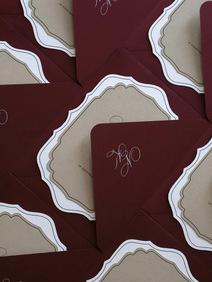 Czerwone kartki papeterii ślubnej z dekoracyjną czcionką w białym kolorze.